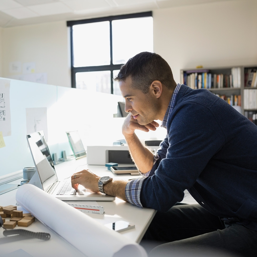 an architect working on a laptop while sitting at his office desk