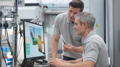 幾個工程師在矯形工廠的屏幕上觀看CNC車床進展情況