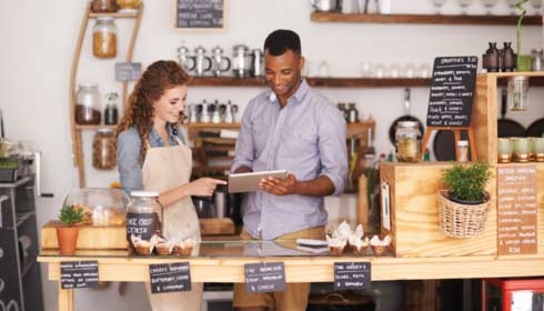 Cropped shop of a handsome coffee shop owner showing a waitress the ropes